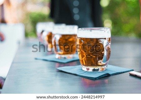 Row of beer glasses on an outdoor table - beer taste refreshing moment under the open sky, capturing the essence of social leisure time.