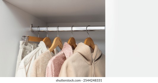 Row of beige casual clothes on the wooden hangers. White empty space for design. Concept of clothing capsule for natural lifestyle - Powered by Shutterstock