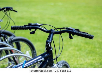 A row of bicycles is parked in a grassy field, showcasing various parts like wheels, tires, frames, handlebars, and forks. These bikes provide transportation and recreation for many - Powered by Shutterstock