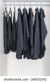 Row Of Black Shirts And Pants Hanging On Coat Hanger In White Wardrobe