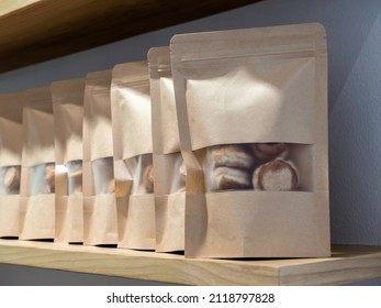 A row of blank craft paper bag packaging with soft cookies inside. Mockup template. Kraft paper zipper Pouch packaging for bakery snacks on wooden shelf.