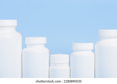 Row Of Blank White Plastic Bottles Of Medicine Pills Or Supplements On Blue Background