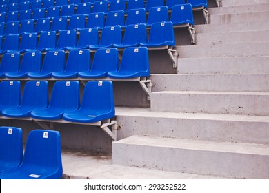 Row of blue numbered seats on a stadium near an aisle with staircase with concrete steps - Powered by Shutterstock