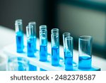 A row of blue test tubes are lined up on a white lab bench. The tubes are filled with clear liquid, and the overall mood of the image is one of scientific experimentation and discovery