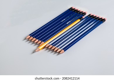 Row Of Blue Wooden Pencils With One Yellow Different Pencil Not Aligned With The Other Pencils