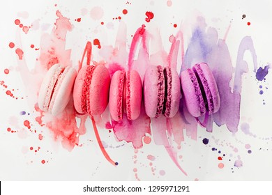 A row of bright macarons of different color on a watercolor background. Pastel colors with a gradient. Art of patisserie concept.