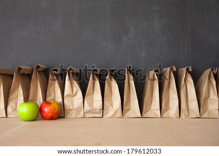A row of brown bags against a blackboard.