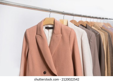 Row of brown coat ,suit and warm knitted  sweater on hanger –white background

 - Shutterstock ID 2120022542