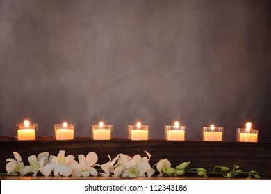 Row of burning candles with white orchid flower,zen concept.
