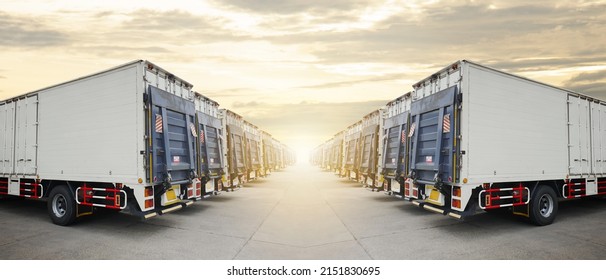 Row Of Cargo Container Trucks With Lifting Ramp Parked Lot At The Sunset Sky. Diesel Truck Lorry. Shipping Container Trucks Freight. Distribution Warehouse. Cargo Transport Logistics.	