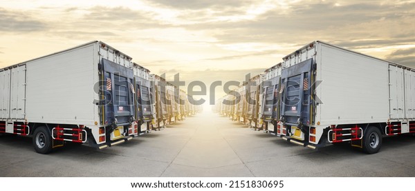 Row\
of Cargo Container Trucks with Lifting Ramp Parked Lot at the\
Sunset Sky. Diesel Truck Lorry. Shipping Container Trucks Freight.\
Distribution Warehouse. Cargo Transport\
Logistics.	