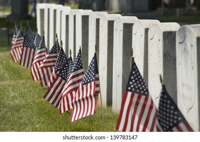 Row of cemetery headstones decorated with American Flags, close up