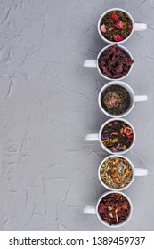 Row of ceramic cups with dried tea leaves. Collection of white cups with assorted tea. Top view with copy space.