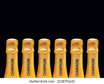 Row of champagne bottles covered in gold foil stamped with the word champagne on the neck against a plain pink background. No people. Copy space. - Shutterstock ID 2218791631