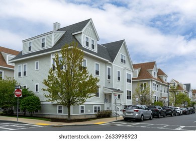 Row of charming multi-unit residences with gable roofs and spring trees in Brighton, Boston, Massachusetts, USA