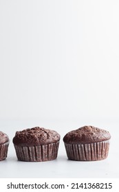 The row of chocolate muffins on a white table - Shutterstock ID 2141368215
