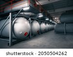 A row of cisterns in the basement illuminated by fluorescent lamps. Industrial tanks for storing liquids and gases under high pressure