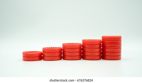 Row of coin rising stacks isolated on white background for money saving plan or financial growth concept. Stacks of red plastic coin shape from table game. Symbolic image