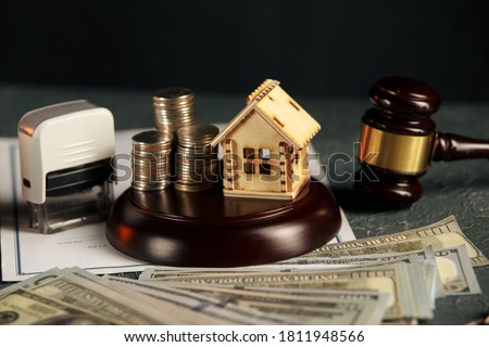 A row of coins on a small house model and a law auction hammer