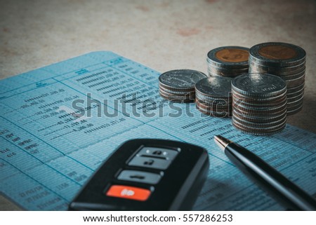 Row of coins,car remote and pen on account book in car finance and banking concept