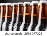 Row cold ice beer bottles with drops of water against brick wall. Concept craft brewery.