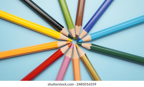 A row of colored pencils are arranged in a circle. The pencils are of different colors and sizes, and they are all lined up next to each other. The arrangement of the pencils creates a sense of unity - Powered by Shutterstock