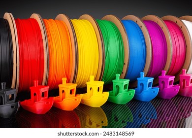 row of colorful 3d printing filament PLA material on environmentally friendly and recyclable paper cardboard spools on black carbon fiber background. modern FDM printer technology concept