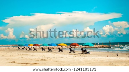 A row of colorful beach umbrellas and beach loungers on Galveston Island Texas.