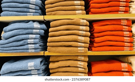 Row of colorful clothes on shelf with size tags. - Shutterstock ID 2376389087