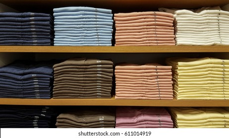 Row Of Colorful Clothes On Shelf With Size Tags.