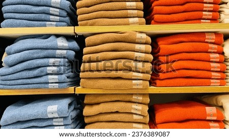 Row of colorful clothes on shelf with size tags.