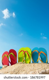 Row of colorful flip flops on beach against sunny sky - Shutterstock ID 186781997