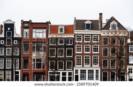 Row of colorful narrow dutch houses with gabled facades and large windows in amsterdam, netherlands