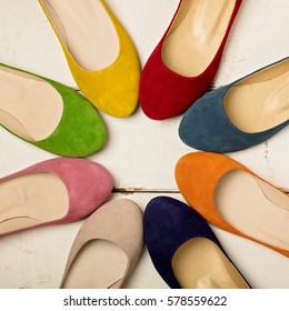 Row Of Colorful Shoes (ballerinas) On A White Wooden Background. Selective Focus