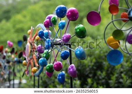 A row of colorful toy windmills against a green background of foliage. Narrow depth of field
