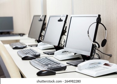 Row of computers with headphones on desk at call center