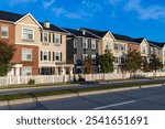 A row of contemporary townhouses with white fencing, located in Mission, BC, Canada. The suburban scene is characterized by a clear blue sky, showcasing urban architecture.