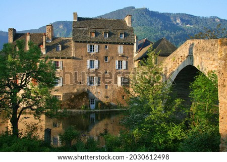 Row of cottages and old bridge across the Lot River soon after sunrise in Mende, Occitanie, France