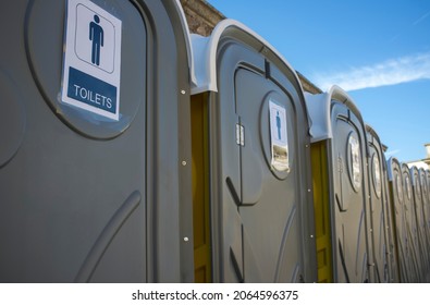 Row of dark grey portable toilets. Outdoors shot