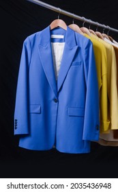 Row Of Different Suit Jacket On Hanger With A Metal Hook Isolated On A Black,background.