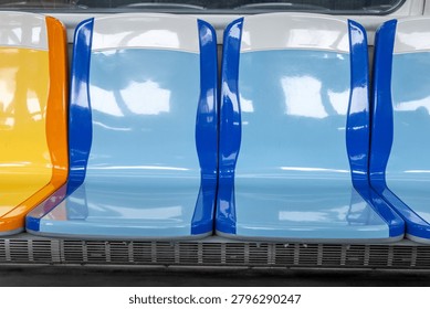 A row of empty blue and white plastic seats inside a clean public transit train or bus.