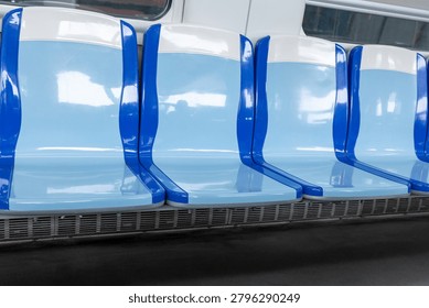 A row of empty blue and white plastic seats inside a clean public transit train or bus.