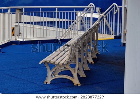 A row of empty white benches rests on a deep blue ship deck, with white railings in the background, at Hook of Holland - Hook of Holland, Netherlands