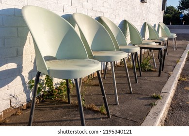 Row Of Empty White Plastic Chairs For Sitting Outside. Cheap Seats On A Pavement For Eating And Drinking In The Sun. Chairs Lined Up Against A Wall Sun Trap. Cheap Hospitality Motorway Service Area.