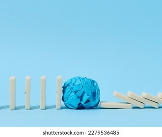 A row of falling dominoes held by a crumpled paper ball, the concept of a strong leader, innovative ideas to save a business from collapse - Shutterstock ID 2279536485