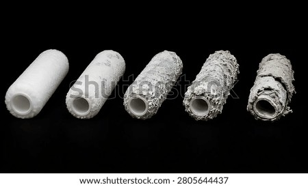 A row of five paint roller covers displaying a clear visual timeline of wear, from clean new fabric to heavily encrusted and worn conditions