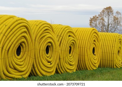 Row Of Five Rolls Of Yellow Farm Drainage Tile On Green Grass