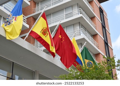 A row of flags from different countries are hanging from the side of a building. The flags include china flag and brazil flag