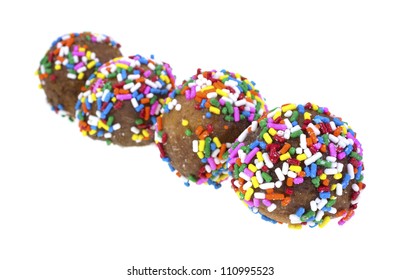 A Row Of Four Donut Holes With Bright Sugar Sprinkles On A White Background.