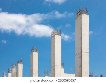 A row of freshly poured concrete pillars in a high rise construction project showing rebar reinforcing steel at the top